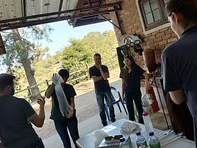 Participantes do curso reunidos em um galpão de haras; um deles segura uma luva de palpação